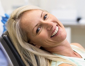 Smiling woman in dental chair after metal free dental restoration