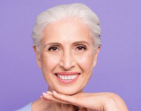 smiling older woman in front of a purple background