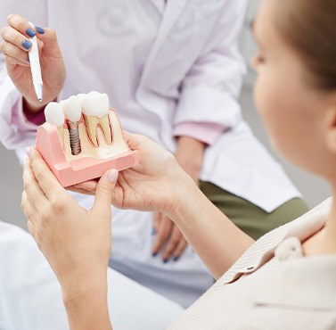 A dentist showing a dental implant model to a patient