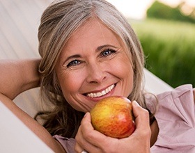 Smiling older woman holding red apple