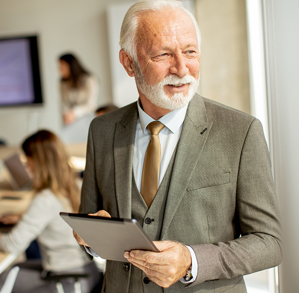 Older businessman holding a tablet in an office