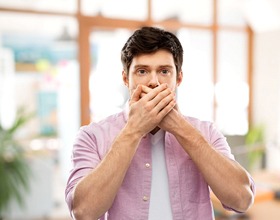 Man hiding his mouth, embarrassed by flaws before dental bonding