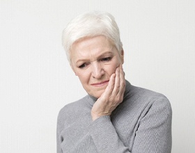 Older woman with white hair experiencing jaw pain due to bruxism