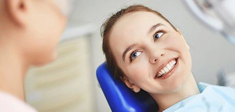 Smiling woman in dental chair after cosmetic dentistry