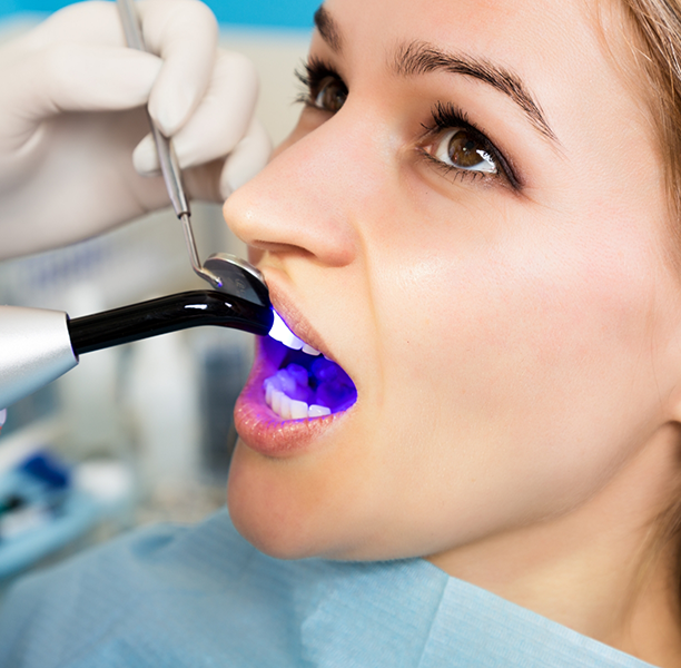 Dental patient having an ultraviolet light shone onto her tooth