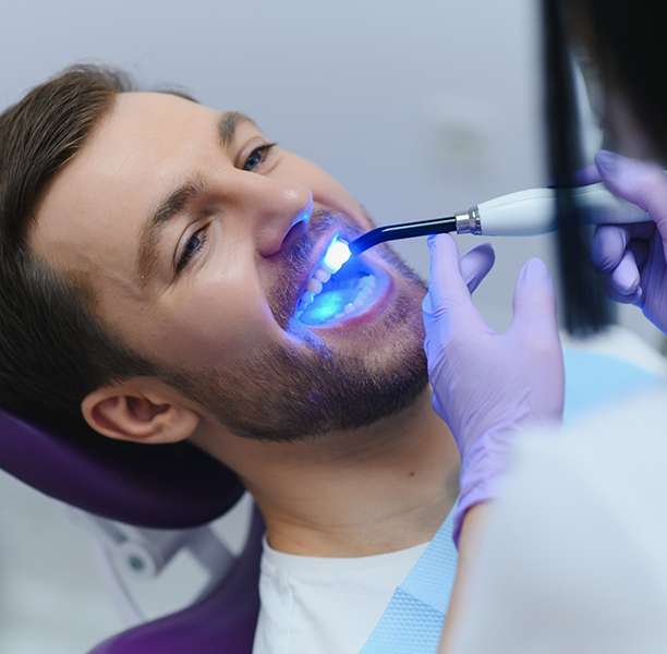 Dental patient having an ultraviolet light applied to his tooth