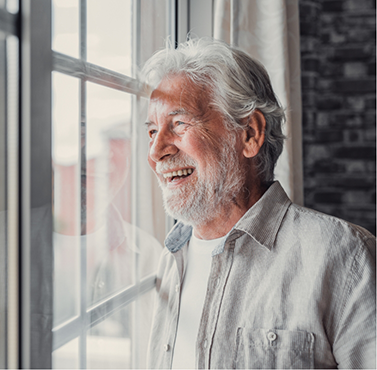 Smiling older man looking out of a window