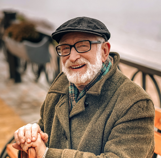Smiling senior man sitting on a bench and holding his cane