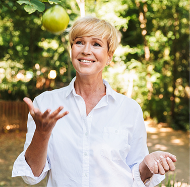 Smiling woman tossing an apple