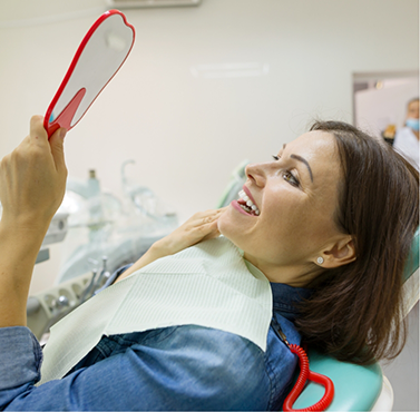 Dental patient admiring her new smile in a mirror