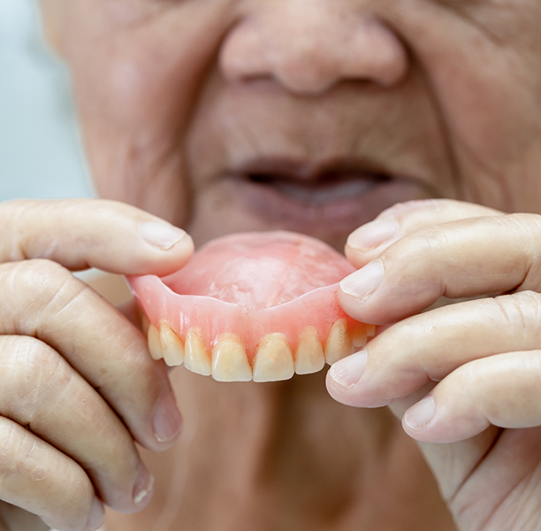 Senior placing a denture in their mouth