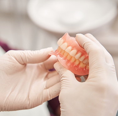 Dental professional holding a set of full dentures