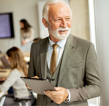 Older businessman holding a tablet in an office