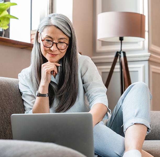 Woman on her couch looking at a laptop
