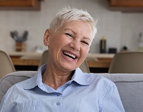 Woman with dentures in Boca Raton, FL sitting on couch 