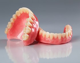 Closeup of complete set of dentures on reflective surface