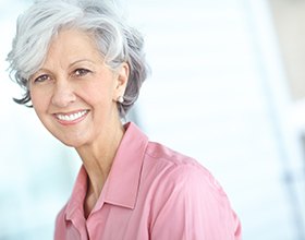 Woman with short gray hair in pink shirt smiling