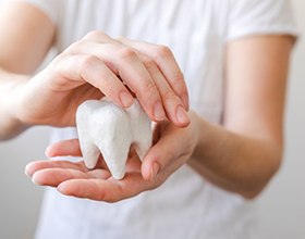 Hands holding a giant plaster model of a tooth
