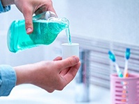 person pouring mouthwash into a small cup