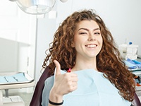 young woman giving a thumbs up in the dental chair
