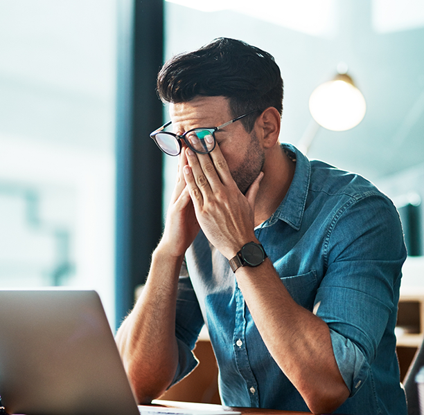 Man at an office desk rubbing his eyes