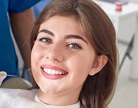 Smiling woman in dental chair after scaling and root planing