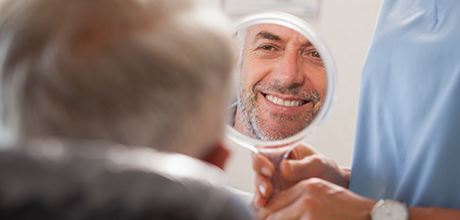 Dentist showing patient smile in mirror after restorative dentistry