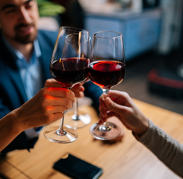 Three people toasting glasses of red wine
