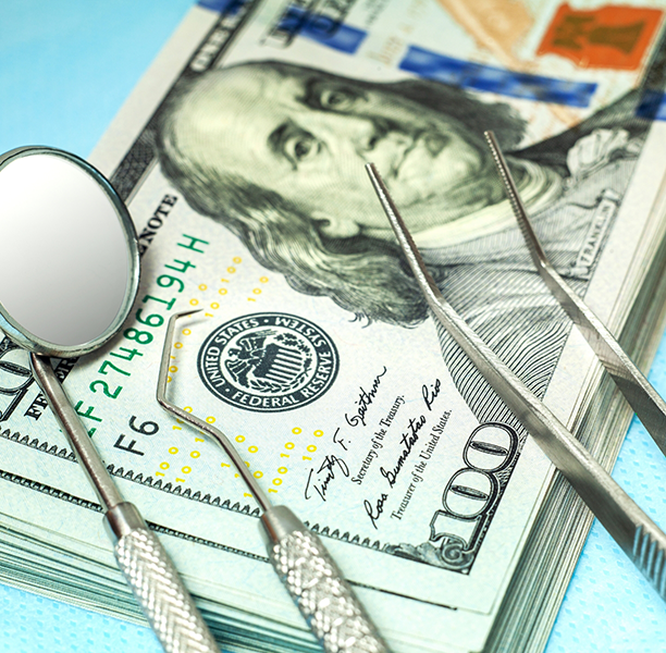 Dental instruments on top of a stack of hundred dollar bills