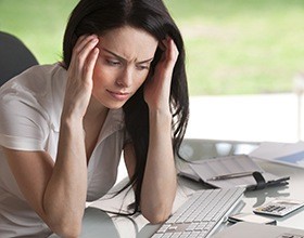 Woman with headache holding temples before T M J treatment