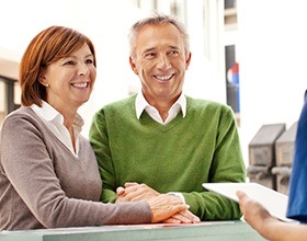 Smiling man and woman discussing equilibration and occlusal adjustment treatments