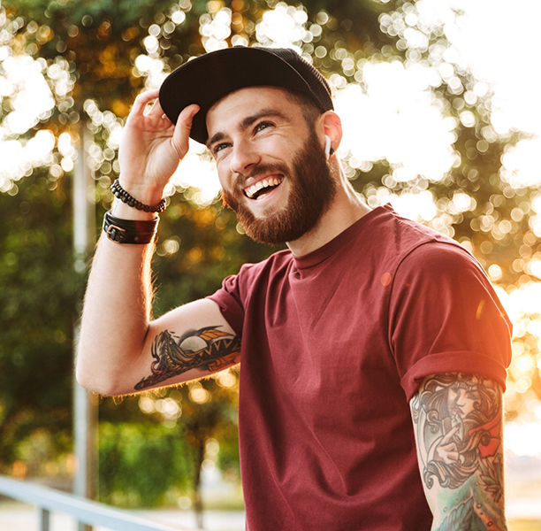Young man with tattoo sleeves smiling in the sun
