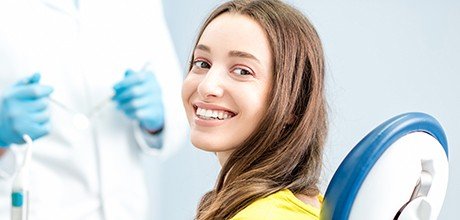 Smiling woman with porcelain veneers in dental chair