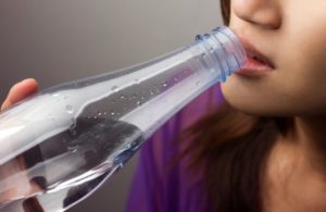 woman drinking water to try to relieve dry mouth