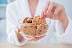 woman in white bathrobe eating cookie during quarantine