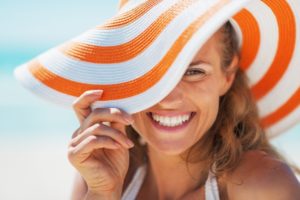 Smiling woman in sun hat and veneers in Boca Raton