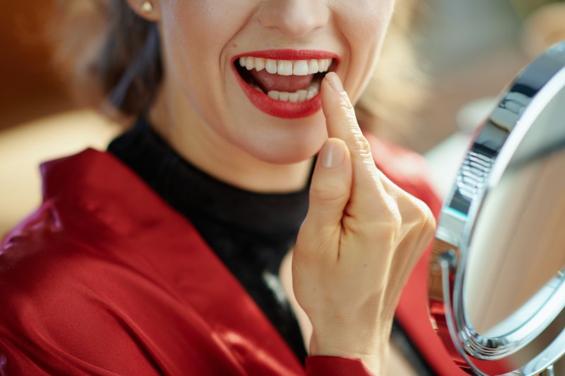 Woman looking at her teeth in mirror.