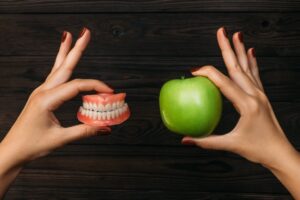 Person holding dentures next to food